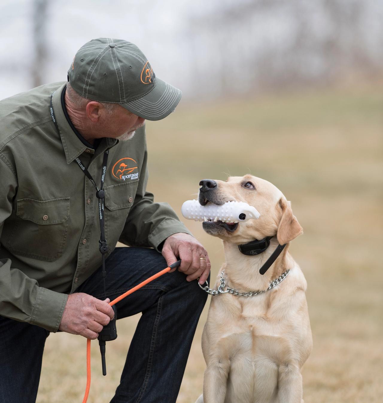 Charlie Jurney kneeling by yellow lab holding white plastic dummy