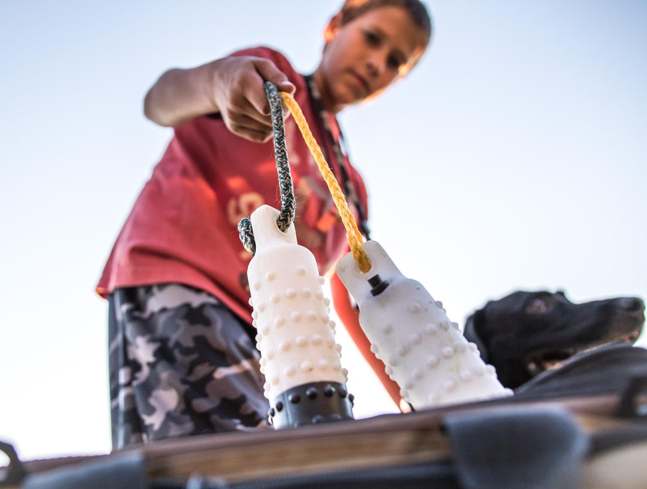 Young boy pulling dummies out of gear back with black lab at side.